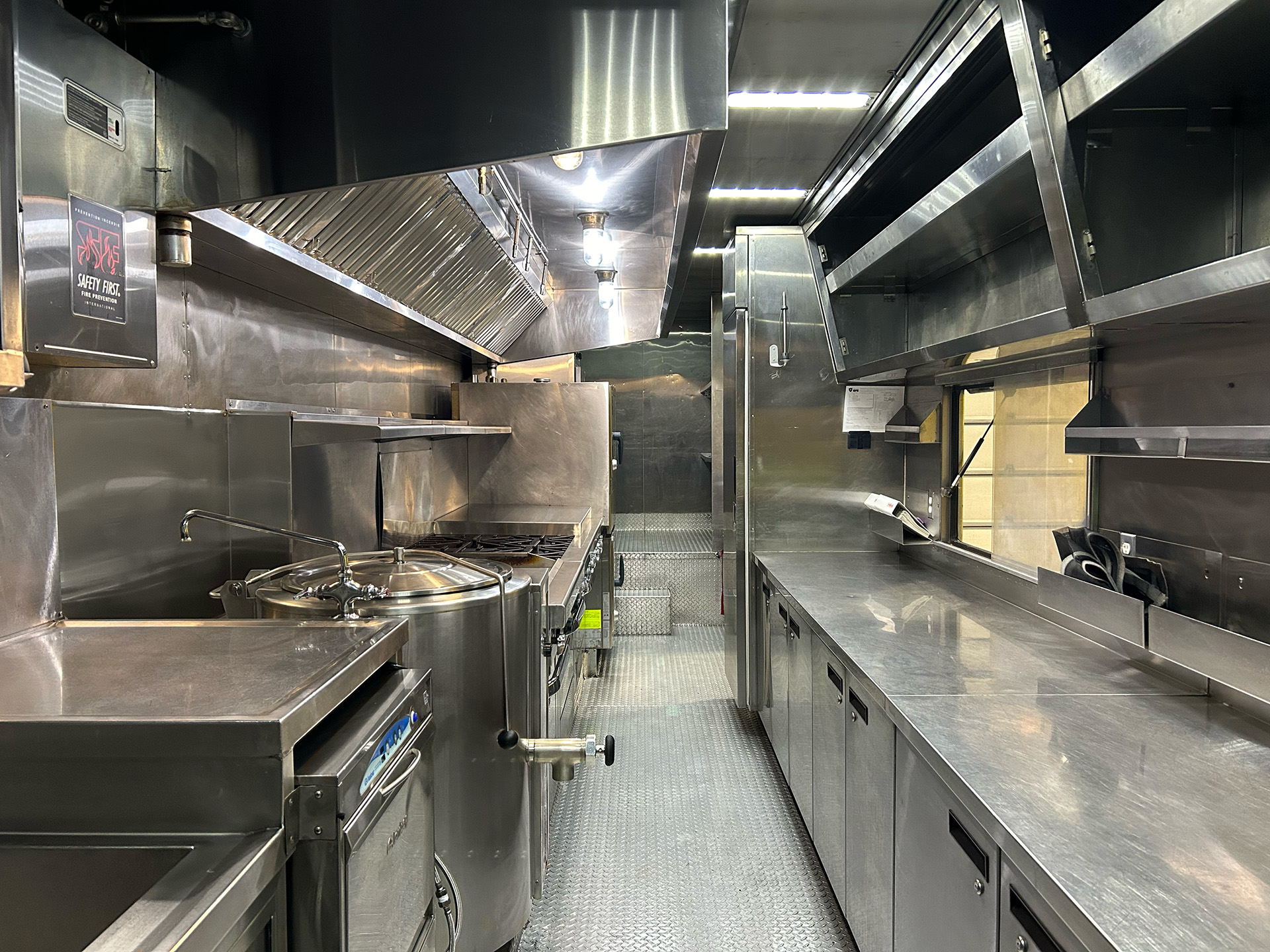 Interior of a professional stainless-steel mobile kitchen, fully equipped.