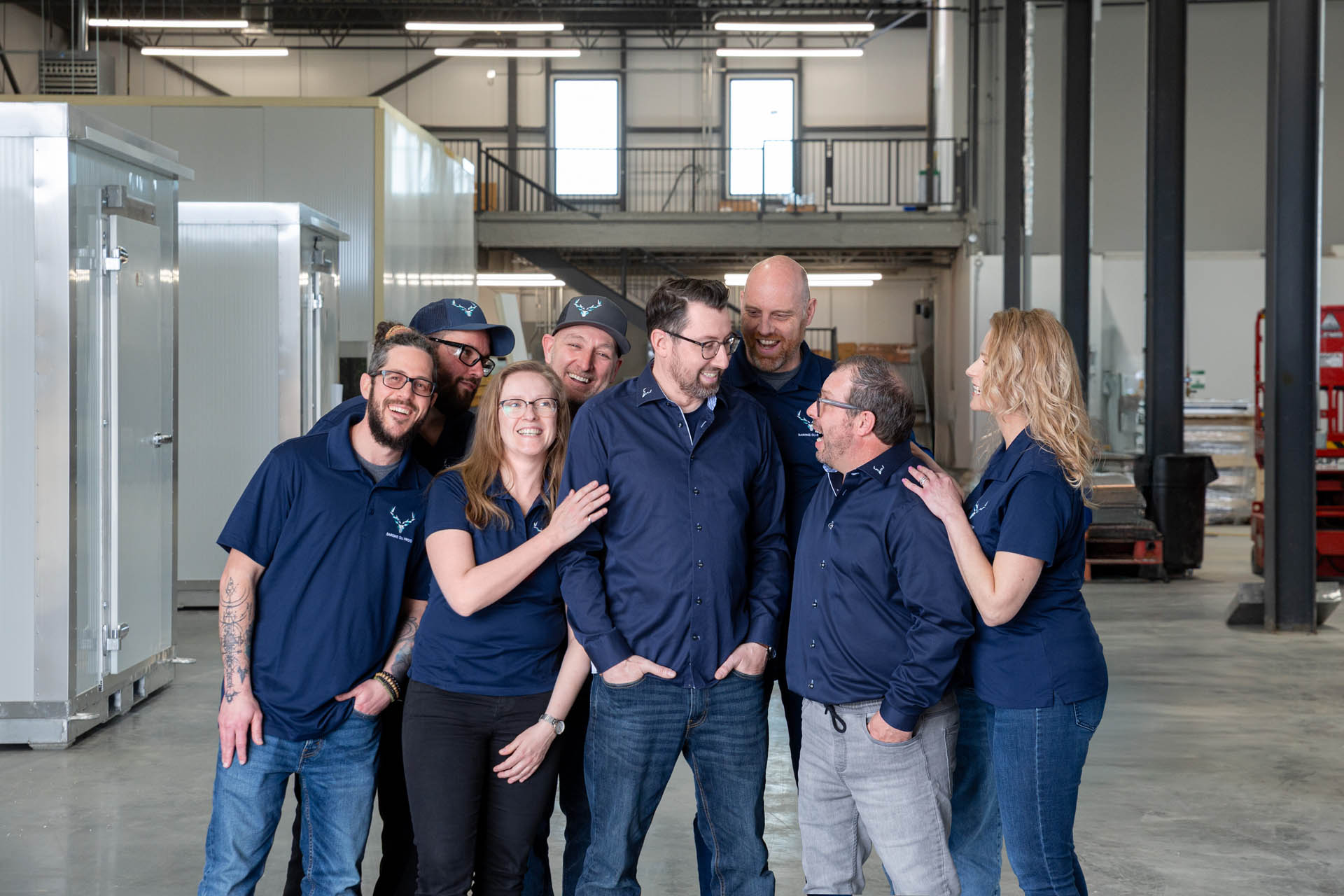The smiling Barons du Froid team in their warehouse, standing between refrigeration units.